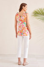 Load image into Gallery viewer, Woman wearing a bright multicolored shoulder tie tank top, white pants and white sandals against a white background with a palm plant.