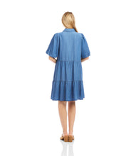 Load image into Gallery viewer, Woman wearing a blue chambray dress and sandals standing against a white background.