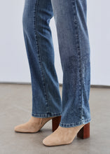 Load image into Gallery viewer, Close up of blue jeans with tonal embellishments and beige boots against a neutral background.