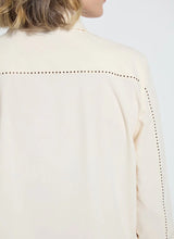 Load image into Gallery viewer, Close-up of a cream-colored blouse with bronze embellishments against a white background.