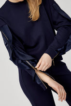 Load image into Gallery viewer, Close-up of woman unzipping the sleeve zipper on a navy blue top against a white background.