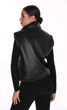 Load image into Gallery viewer, A woman shown from the back wearing a black faux-leather vest with brown fur trim over a black long-sleeve top and black pants, against a plain white background.