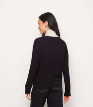 Load image into Gallery viewer, A woman shown from the back wearing a black long-sleeve knit turtleneck sweater with a contrasting light beige/cream collar, paired with black trousers, against a plain white studio background.