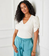 Load image into Gallery viewer, Redefine your wardrobe essentials with the Rayne Ribbed Twist Sleeve V-Neck Top. Crafted from a soft, stretchy cotton ribbed knit, this top hugs your silhouette with effortless charm. The standout twist sleeve design adds a modern touch to the classic V-neck style, making it perfect for layering or wearing solo. Chic, versatile, and timeless—it's a piece you'll reach for again and again.