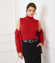 Load image into Gallery viewer, Woman wearing a red sleeveless ribbed turtleneck sweater, red cardigan, black skirt and black belt against a white wall.