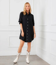 Load image into Gallery viewer, Woman wearing a black shirt dress and white cowboy boots against a white wall.