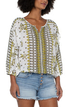 Load image into Gallery viewer, This fresh, bold and fabulous blouse has all the feminine details featuring ruffle sleeves and a beautiful batik floral print. This romantic bandana printed top is the perfect statement piece. Pairs beautifully with everything from your favorite pants to shorts. Colors -Geo floral print; black, white, greens. Lightweight gauze. Ruffle sleeve. Dolman sleeve. Pullover. Smocked waistband. Elastic at wrists.