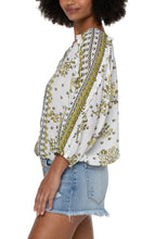 Load image into Gallery viewer, This fresh, bold and fabulous blouse has all the feminine details featuring ruffle sleeves and a beautiful batik floral print. This romantic bandana printed top is the perfect statement piece. Pairs beautifully with everything from your favorite pants to shorts. Colors -Geo floral print; black, white, greens. Lightweight gauze. Ruffle sleeve. Dolman sleeve. Pullover. Smocked waistband. Elastic at wrists.