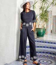Load image into Gallery viewer, Refined yet effortlessly comfortable, the Sherrit Scallop Drawstring Pants by Karen Kane blend elegance with everyday ease. Crafted from black cotton woven fabric, these wide-leg pants feature delicate cream embroidery and a scalloped hem. Perfect for casual outings, workdays, or evening wear, these versatile embroidered pants pair beautifully with blouses, tanks, or structured tops.