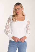 Load image into Gallery viewer, Woman wearing a white blouse with sheer sleeves and jeans against a plain background.