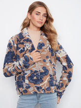 Load image into Gallery viewer, A woman modeling a long-sleeve button-up coat with a camel, navy, and white abstract floral pattern, paired with light-wash blue jeans and black ankle boots, standing against a white wall.