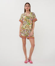 Load image into Gallery viewer, Woman wearing a colorful jungle floral print top and shorts and pink sandals against a white background.