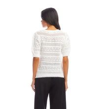 Load image into Gallery viewer, Woman wearing an off-white, short sleeve crochet top and black pants against a white background.