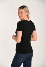Load image into Gallery viewer, Model wearing a short sleeve black top with sequin flowers and blue jeans against a white background.