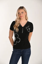 Load image into Gallery viewer, Model wearing a short sleeve black top with sequin flowers and blue jeans against a white background.