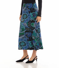 Load image into Gallery viewer, Model wearing a blue, green, purple multi-print midi skirt, black top and black short -heeled sandals against a white background.