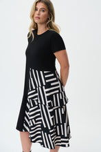 Load image into Gallery viewer, If you are looking for a comfortable and highly fashionable dress, our Soren knit woven dress is a beautiful addition to your wardrobe. A one piece, pullover dress, our Soren is a solid black on top and down one side of the dress, while the other half of its skirting is voluminous with a ruffled abstract pattern hem. This flowy dress feels as gorgeous as it looks! Color- Black and white. One piece dress. Abstract print on one side. Solid on the other. Solid color top. Ruffled hem on one side. No pockets.