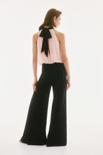 Load image into Gallery viewer, Exude sophistication in this wide leg jumpsuit, showcasing a contrasting chiffon blouson upper and a luxurious silky knit bottom. This one-piece garment features a mock collar with a lovely back bow tie. The fashionable wide leg combined with the shoulder-baring halter style creates a stunning ensemble. Part of Joseph Ribkoff's Signature collection.