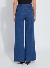 Load image into Gallery viewer, Person wearing blue wide-leg trouser jean, black tee and black sandals against a white background.