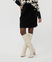Load image into Gallery viewer, Elevate your style with our Knitted Short Skirt. This versatile piece features a cozy knitted texture and includes shiny gold buttons, making it perfect for both casual and dressy occasions. The skirt's short length and snug fit accentuate your silhouette, while the elastic waistband provides comfort and ease of movement. Pair it with a tucked-in blouse or a cozy sweater for a chic, effortlessly stylish look.