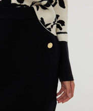 Load image into Gallery viewer, Elevate your style with our Knitted Short Skirt. This versatile piece features a cozy knitted texture and includes shiny gold buttons, making it perfect for both casual and dressy occasions. The skirt's short length and snug fit accentuate your silhouette, while the elastic waistband provides comfort and ease of movement. Pair it with a tucked-in blouse or a cozy sweater for a chic, effortlessly stylish look.