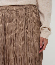 Load image into Gallery viewer, Model wearing a shiny pleated taupe skirt and beige sweater against a white background.