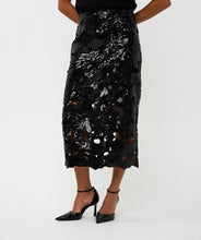 Load image into Gallery viewer, Model wearing a long black sequin floral cutout skirt and black heels against a white background.