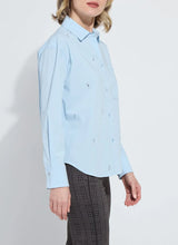 Load image into Gallery viewer, Woman wearing a light blue shirt with embellishments and dark plaid pants against a white background.