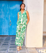Load image into Gallery viewer, Woman wearing a green and cream floral and leaf print ruffle sleeveless top and matching pant posing in front of blue door.