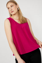 Load image into Gallery viewer, Woman wearing a bright pink sleeveless top and black pants against a white background.