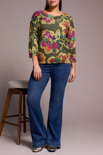 Load image into Gallery viewer, Woman wearing a floral top, blue jeans and metallic flats against a plain background with a barstool in the background.