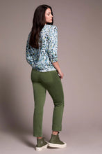 Load image into Gallery viewer, Woman wearing a patterned green, blue, white sweater, green pants and green sneakers against a pale pink background.