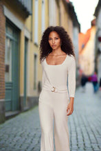Load image into Gallery viewer, Woman in a white outfit standing on a street with blurred background.