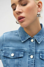 Load image into Gallery viewer, The Joseph Ribkoff Sybella Stretch Denim Jacket is a perfect fusion of classic and modern design. Made from eco-friendly Repreve® stretch denim, this piece features intricate eye-catching embroidery and sparkling rhinestones for a unique touch. With a traditional shirt collar, button closure, and functional chest pockets, it blends style and practicality. The medium blue wash makes it a versatile addition to any wardrobe, ideal for layering with both casual and dressy outfits.