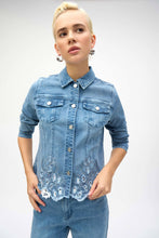 Load image into Gallery viewer, The Joseph Ribkoff Sybella Stretch Denim Jacket is a perfect fusion of classic and modern design. Made from eco-friendly Repreve® stretch denim, this piece features intricate eye-catching embroidery and sparkling rhinestones for a unique touch. With a traditional shirt collar, button closure, and functional chest pockets, it blends style and practicality. The medium blue wash makes it a versatile addition to any wardrobe, ideal for layering with both casual and dressy outfits.