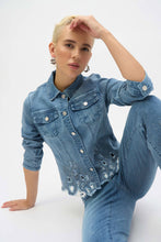 Load image into Gallery viewer, The Joseph Ribkoff Sybella Stretch Denim Jacket is a perfect fusion of classic and modern design. Made from eco-friendly Repreve® stretch denim, this piece features intricate eye-catching embroidery and sparkling rhinestones for a unique touch. With a traditional shirt collar, button closure, and functional chest pockets, it blends style and practicality. The medium blue wash makes it a versatile addition to any wardrobe, ideal for layering with both casual and dressy outfits.