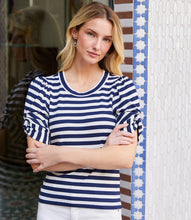 Load image into Gallery viewer, Woman wearing a blue and white striped shirt standing in front of a colorful wall.