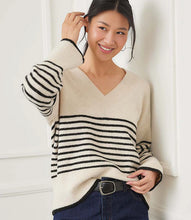Load image into Gallery viewer, Woman wearing an ecru sweater with black stripes and jeans and belt against a white wall.