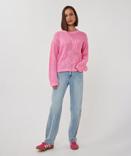 Load image into Gallery viewer, Person wearing an open knit pink sweater with design, blue jeans and pink sneakers on a plain background.