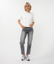 Load image into Gallery viewer, Woman wearing an off-white top with a rhinestone neckline, silver earrings, grey pants and white sneakers against a white background.