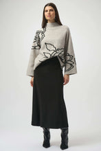 Load image into Gallery viewer, Woman wearing a boxy sweater in light grey with a black floral design, black skirt and black boots against a white background.