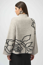Load image into Gallery viewer, Woman wearing a boxy sweater in light grey with a black floral design and black skirt against a white background.