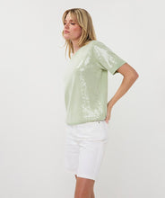 Load image into Gallery viewer, Woman wearing a light green sequin top and white shorts on a white background.
