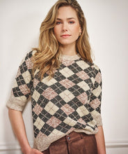 Load image into Gallery viewer, Woman wearing a short sleeve argyle sweater and brown pants against a white wall.