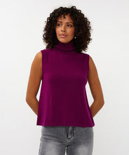 Load image into Gallery viewer, Woman wearing a purple sleeveless turtleneck sweater top and grey jeans against a white background.