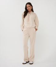 Load image into Gallery viewer, Woman wearing a beige hoodie, matching pants and white sneakers against a white background.