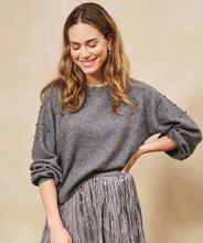 Load image into Gallery viewer, Woman wearing a gray sweater with grey pearls and a grey skirt against a beige background.