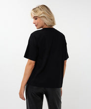 Load image into Gallery viewer, Woman wearing a black t-shirt and black pants against a white background.