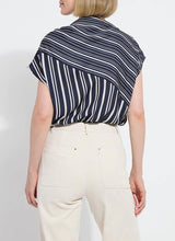Load image into Gallery viewer, The Tamar Stripe Bow-Tie Neck Top is a standout piece, designed in a nautical collage color with distinctive stripes for a timeless, chic appeal. Made from premium Lightweight Satin, this top offers a luxurious feel while maintaining effortless wearability. Its relaxed, boxy fit is complemented by stylish details like a bow tied to one shoulder and a rounded, high-low shirttail hem. Perfect for casual yet polished ensembles, the Tamar Stripe Bow-Tie Neck Top is a versatile addition.