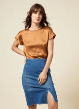 Load image into Gallery viewer, Crafted from 4-way stretch Knit Denim, the Tess Braided Denim Pencil Skirt boasts a knee-length design and boasts a patented waistband, sand blasting, and patch pockets. With princess seaming, a left-front vent, and hand braided details at the waist, this skirt is a true standout!
